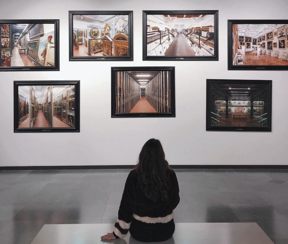 Woman sitting on a bench enjoying art at an art gallery.