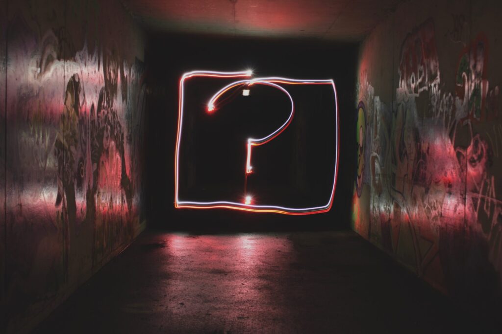 Artistic lighting of a question mark in a dark alley.